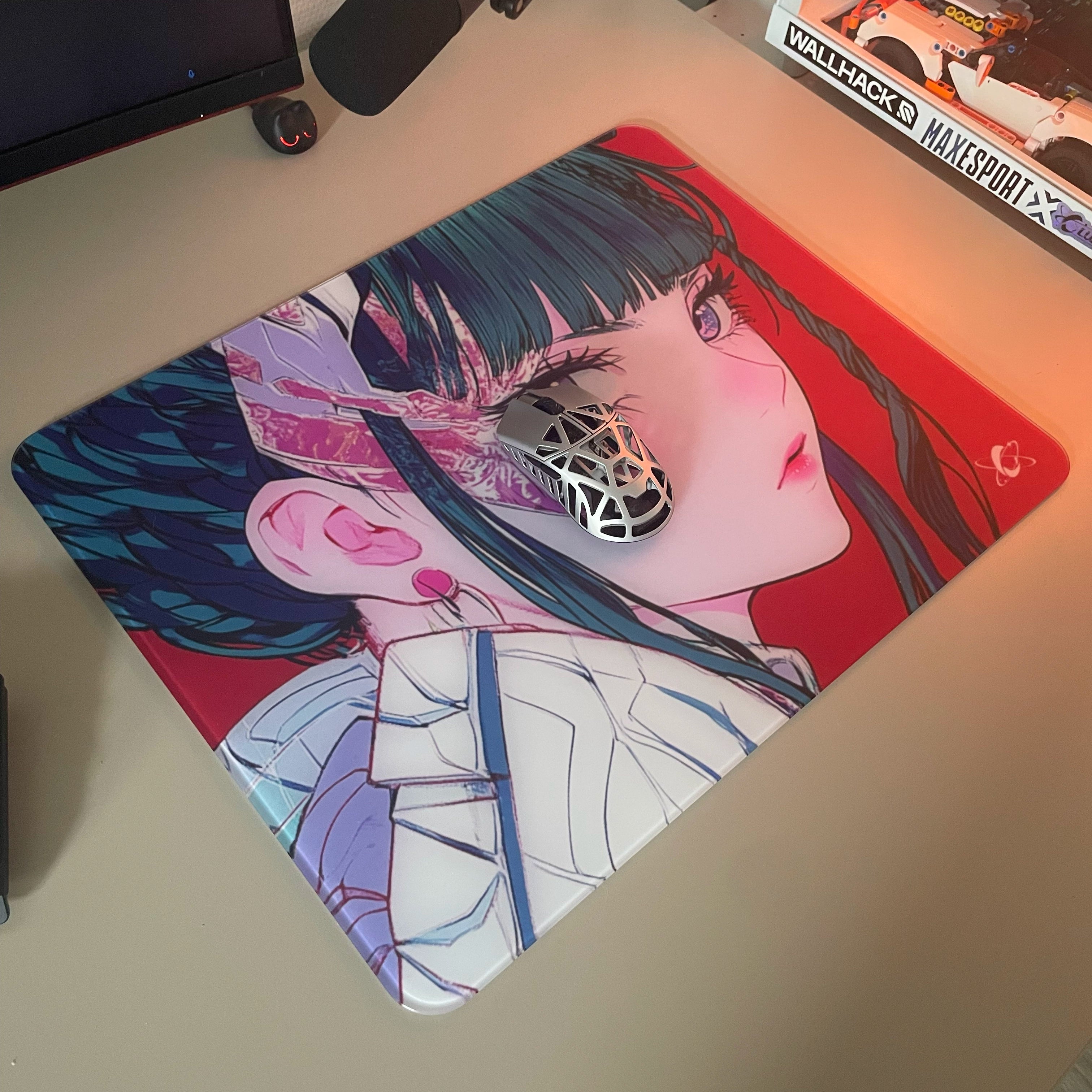 Clustrs Akira glass mouse pad featuring vibrant red anime artwork, shown in a gaming desk setup with a metallic honeycomb-style mouse.