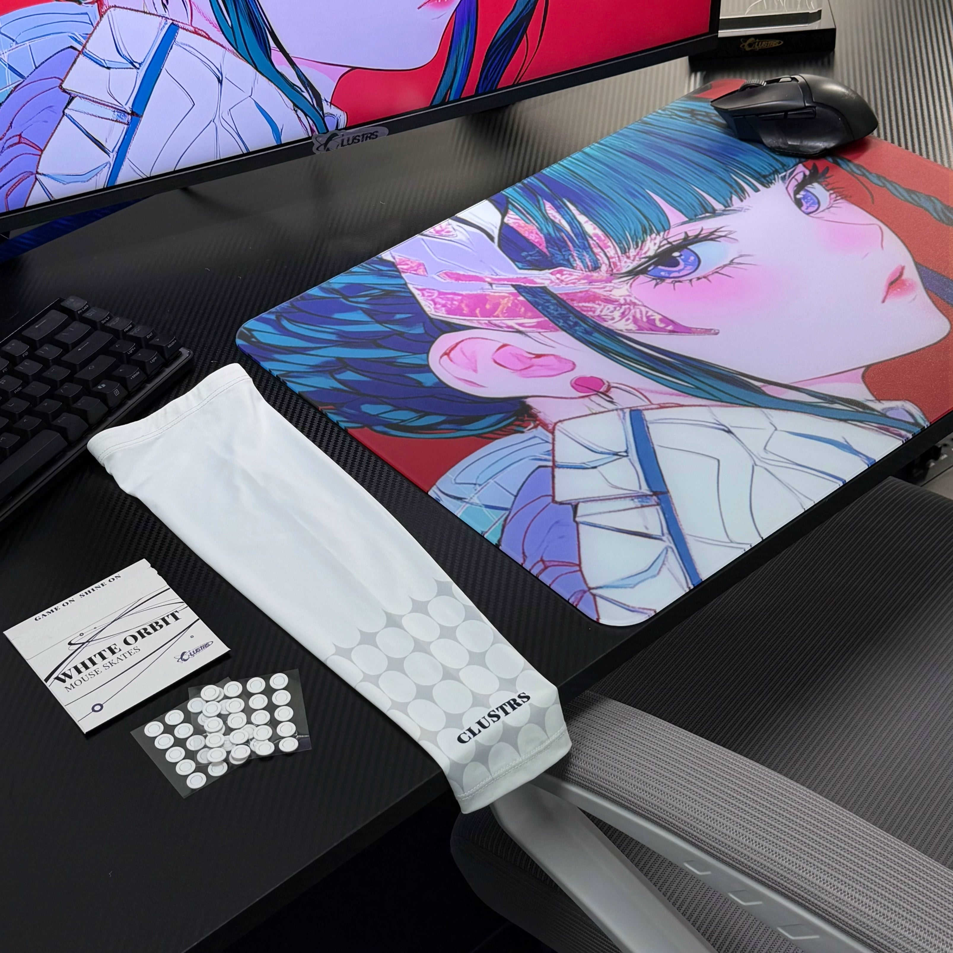 Clustrs Akira glass mouse pad bundle with red anime artwork, displayed on a carbon-fiber desk alongside the white Clustrs arm sleeve and White Orbit mouse skates.