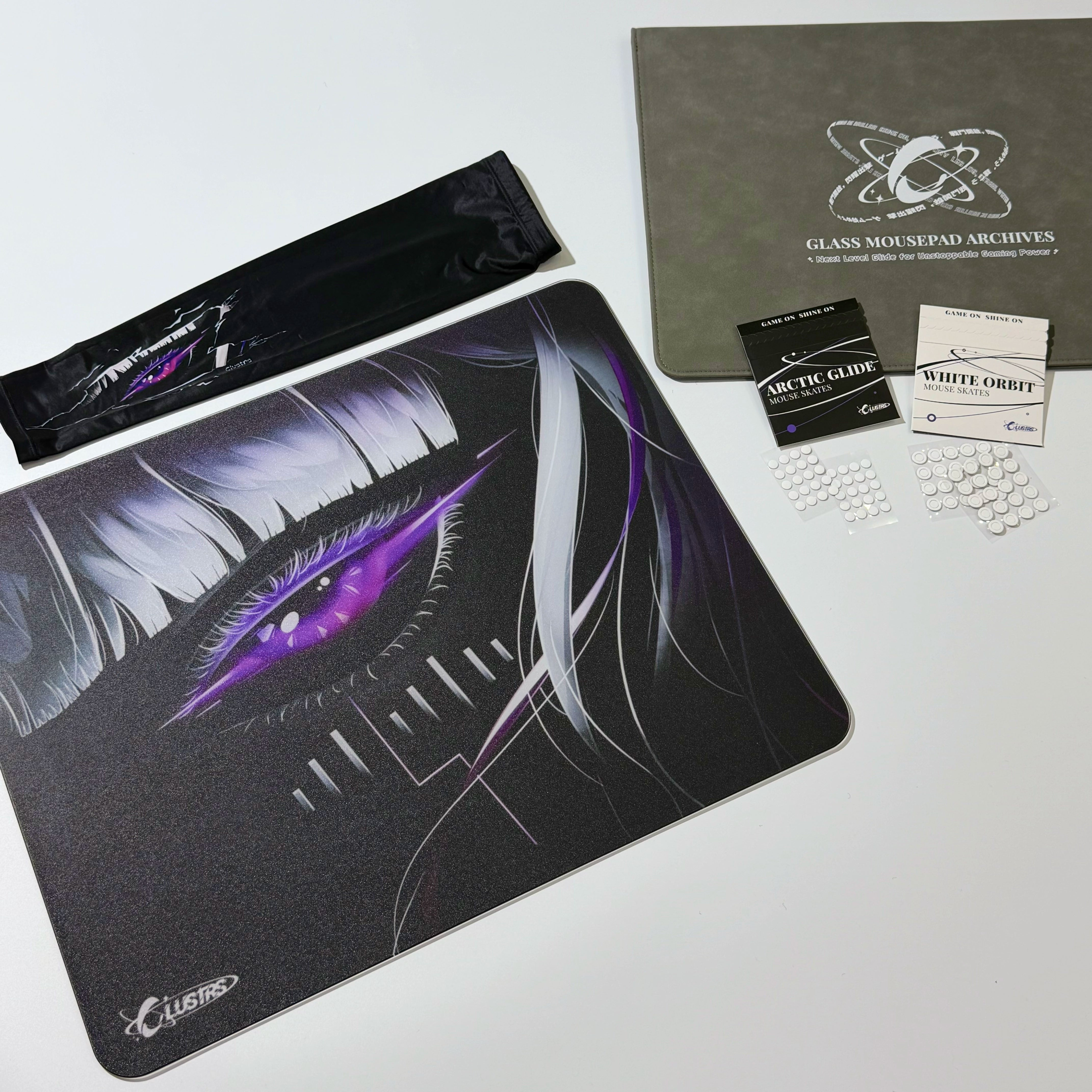 Complete Astra’s Gaze bundle featuring the Clustrs Glass Pad Pro with cyberpunk purple eye design, matching sleeve, Arctic Glide and White Orbit mouse skates, and protective storage case.