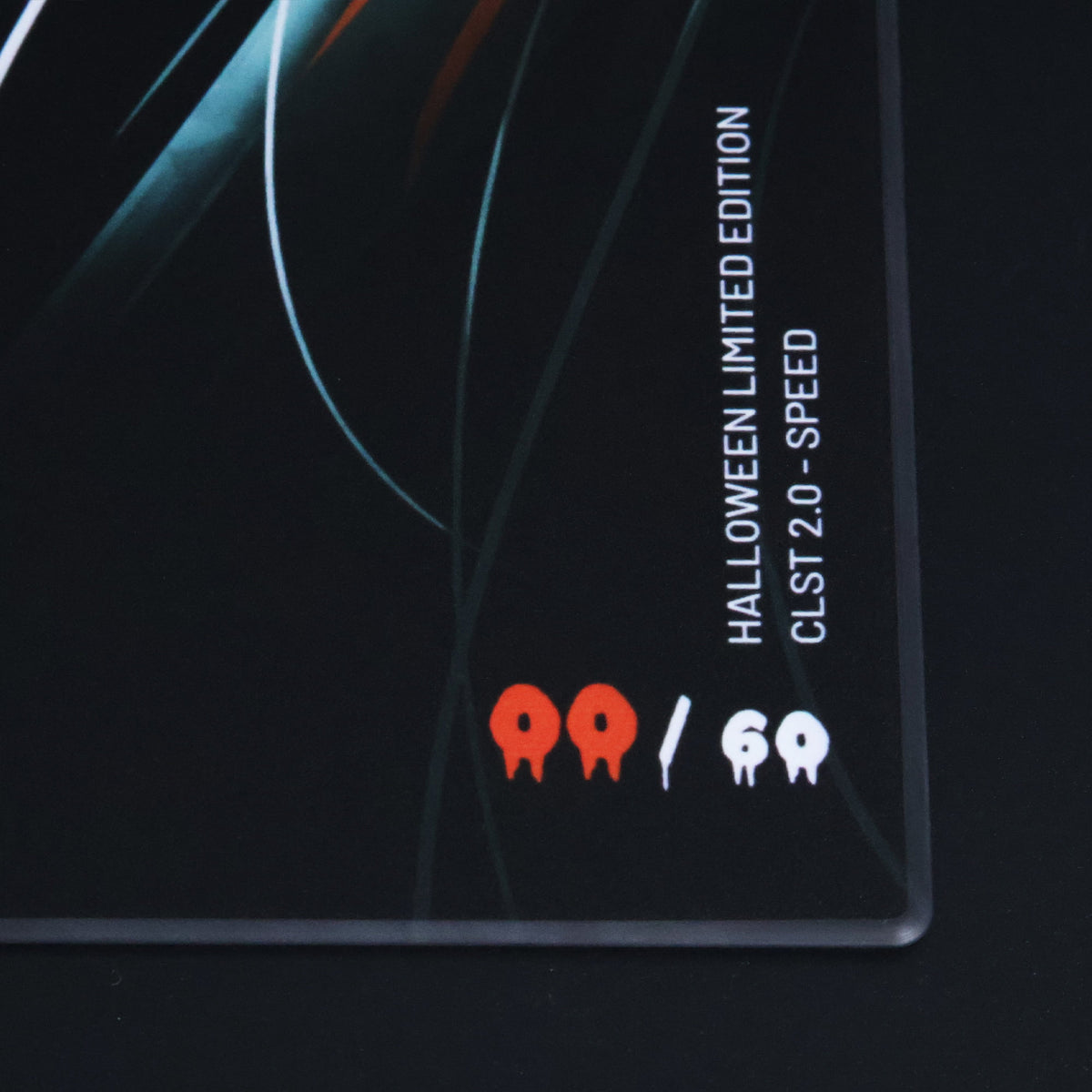 Angled close-up of the EMBER glass mousepad, showing its orange eye artwork, printed design, and rounded edge.