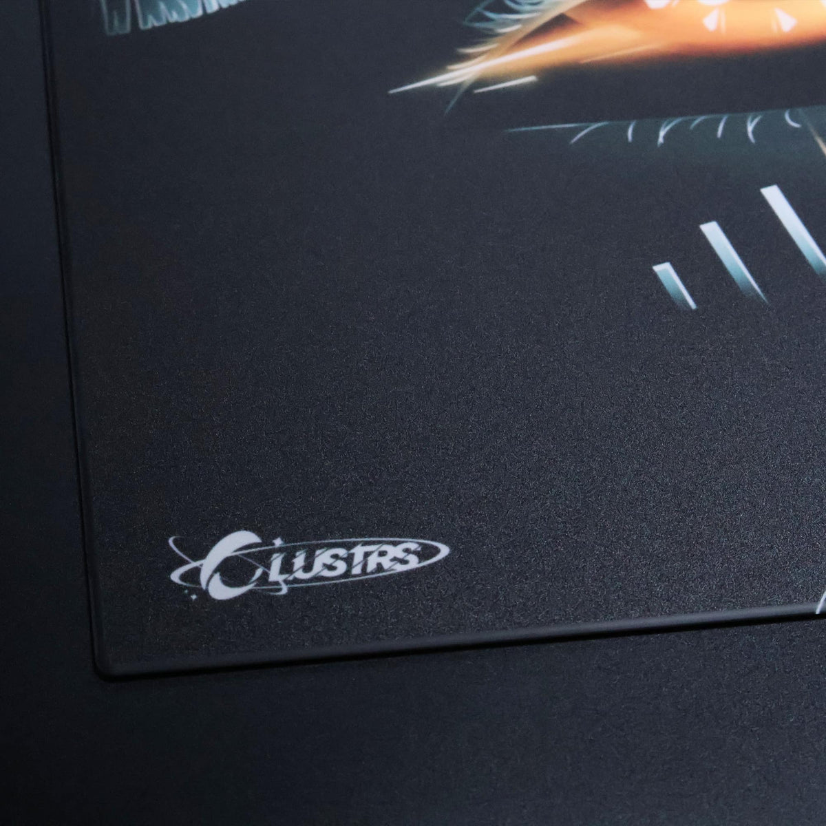 Close-up of the orange eye artwork and CLUSTRS logo on the EMBER Halloween glass mousepad.