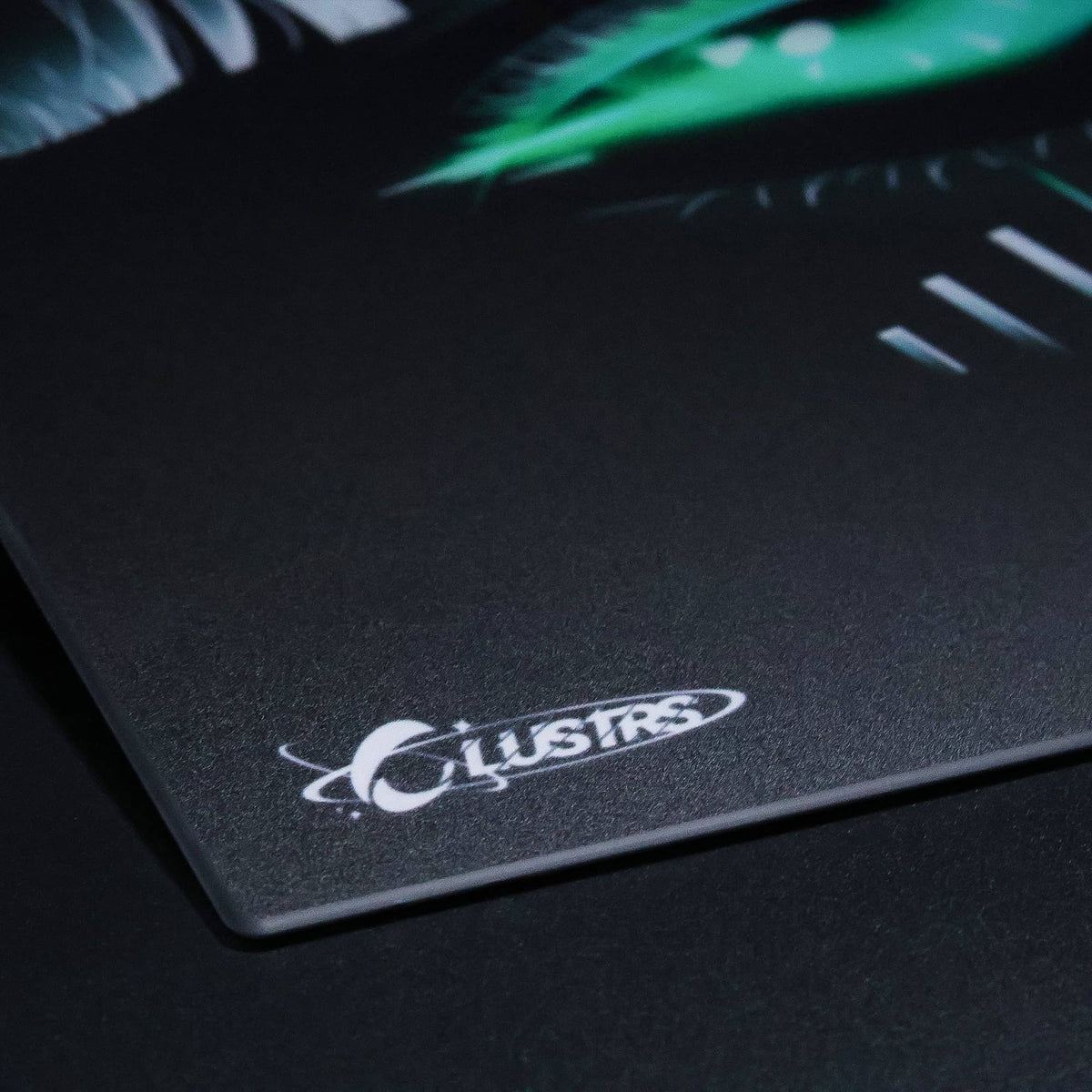 Close-up of the CLUSTRS logo and textured surface on the dark SPECTER Halloween glass mousepad.