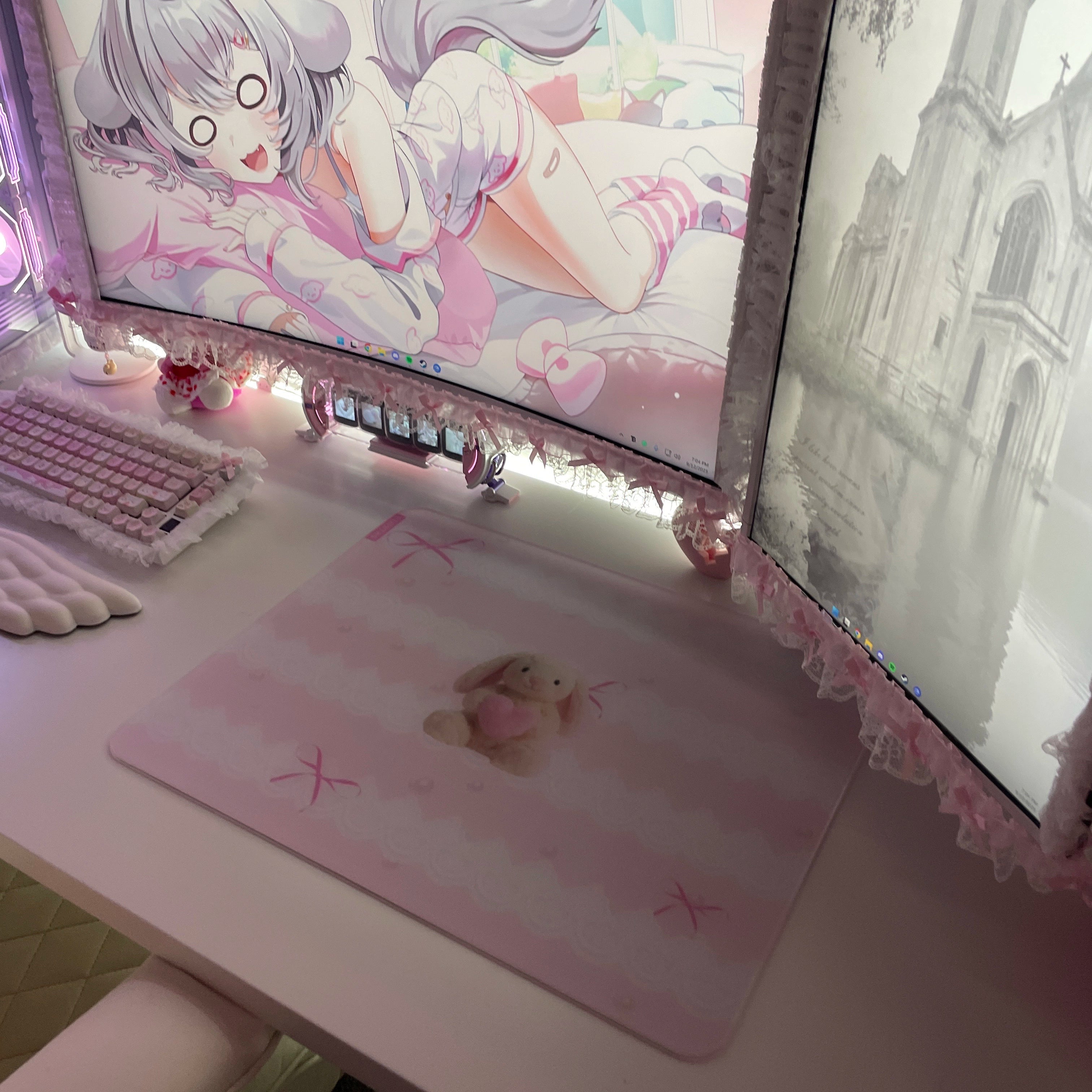 Clustrs Pearl Bunny glass mousepad on a pink kawaii gaming desk setup with wing wrist rest, pastel keyboard, and dual curved monitors.